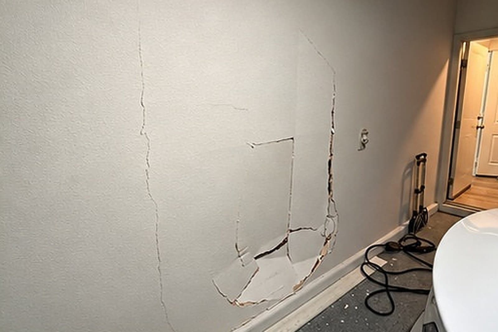 Garage wall with a long crack and a broken patch of drywall