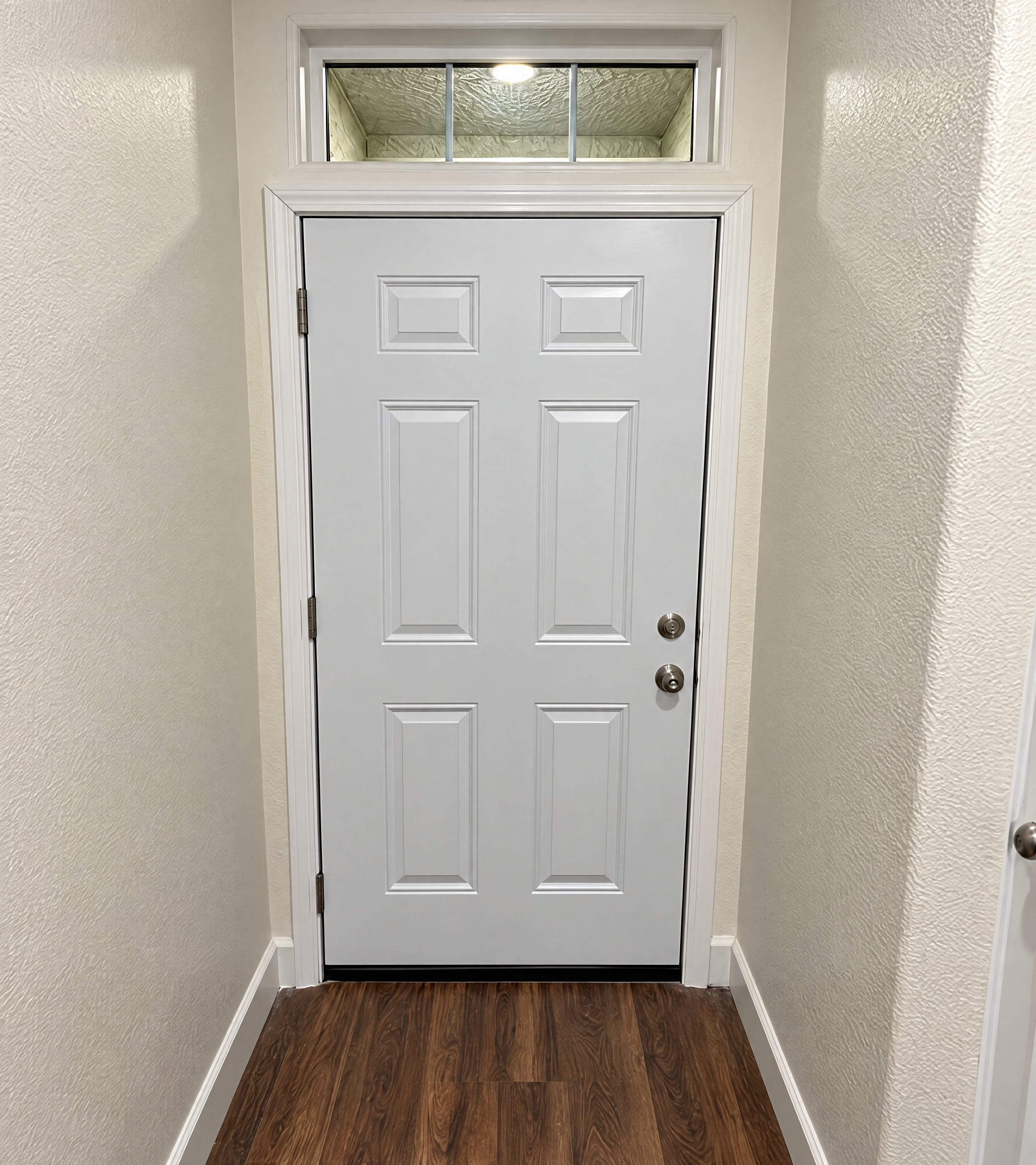 White six-panel entry door in a hallway