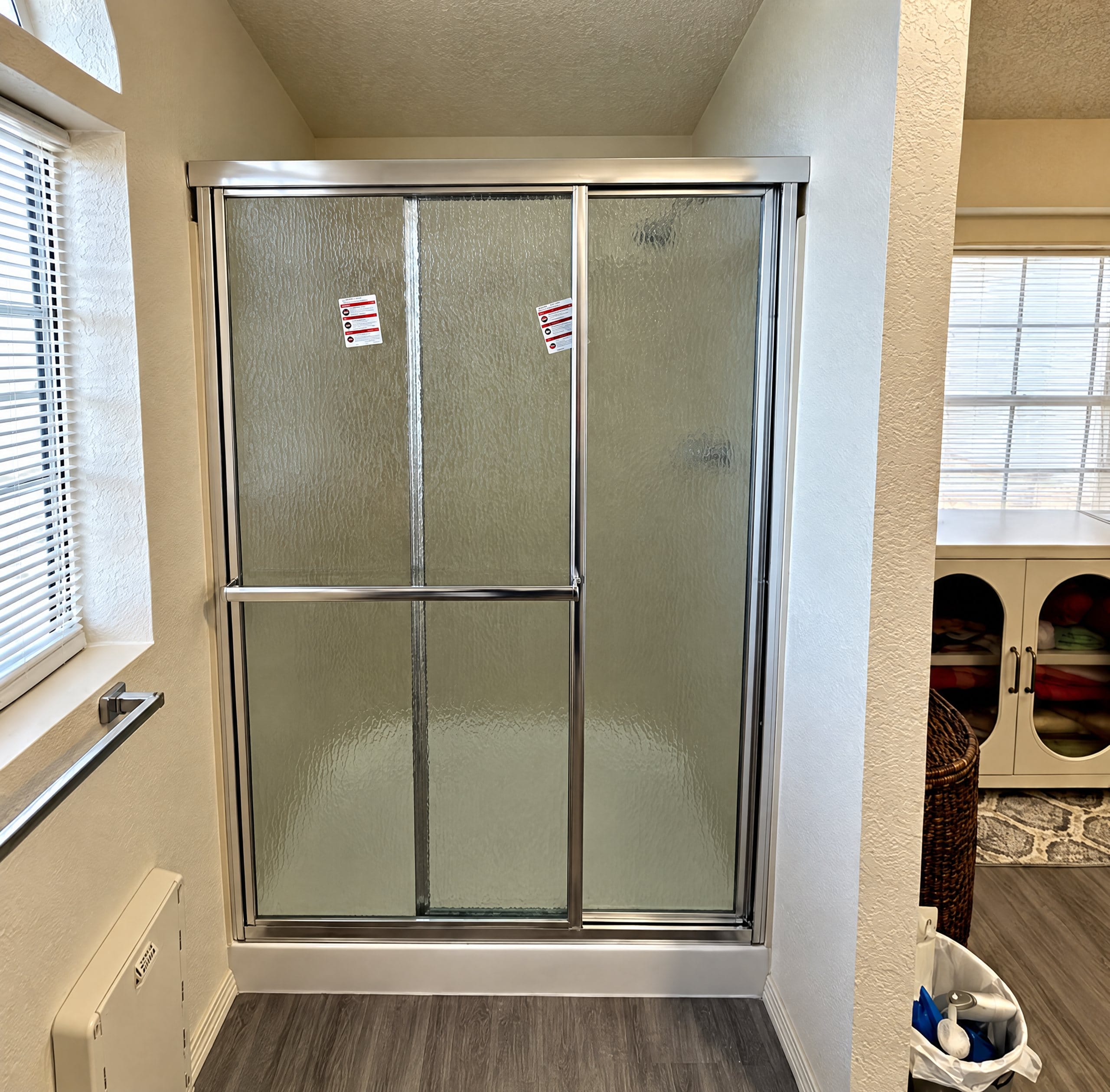 Framed sliding shower door with textured glass