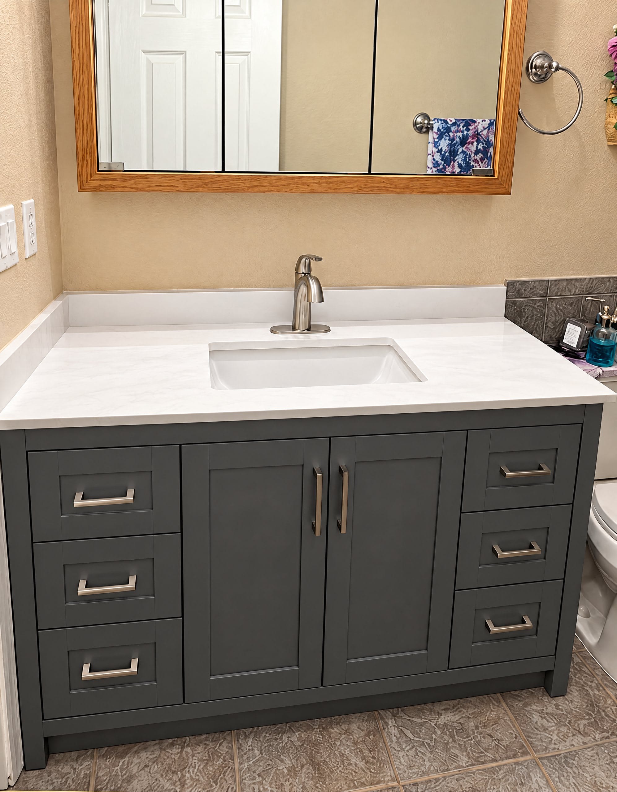 Dark green bathroom vanity with a white top and new faucet